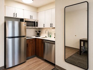 A compact kitchen with a stainless steel refrigerator, a microwave, and a dishwasher. - Staybridge Suites Middleton Madison-West by IHG (Middleton)