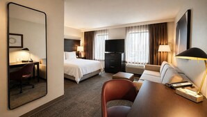 A hotel room with a bed, desk, chair, TV, and a large mirror. - Staybridge Suites Middleton Madison-West by IHG (Middleton)