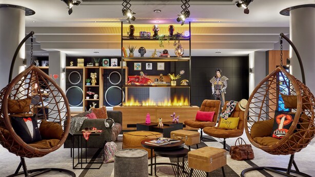 A modern living room with a fireplace, comfortable seating, and a decorative shelf with various items.