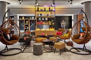 Uma sala de estar moderna com lareira, assentos confortáveis e uma estante decorativa com diversos objetos.