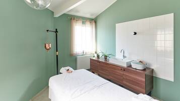 A bedroom with a bed, a wooden dresser, a white sink, and a large mirror.