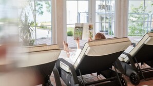 A sunlit room with wicker lounge chairs and a large window. - Hotel Whitman (Ascheberg)