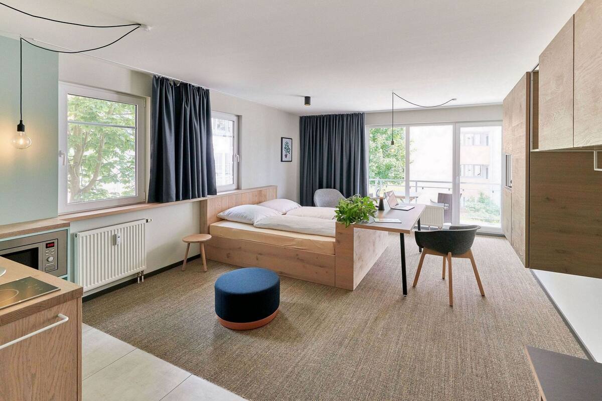 Un dormitorio moderno con una cama, mesita de noche y una pequeña zona de escritorio.