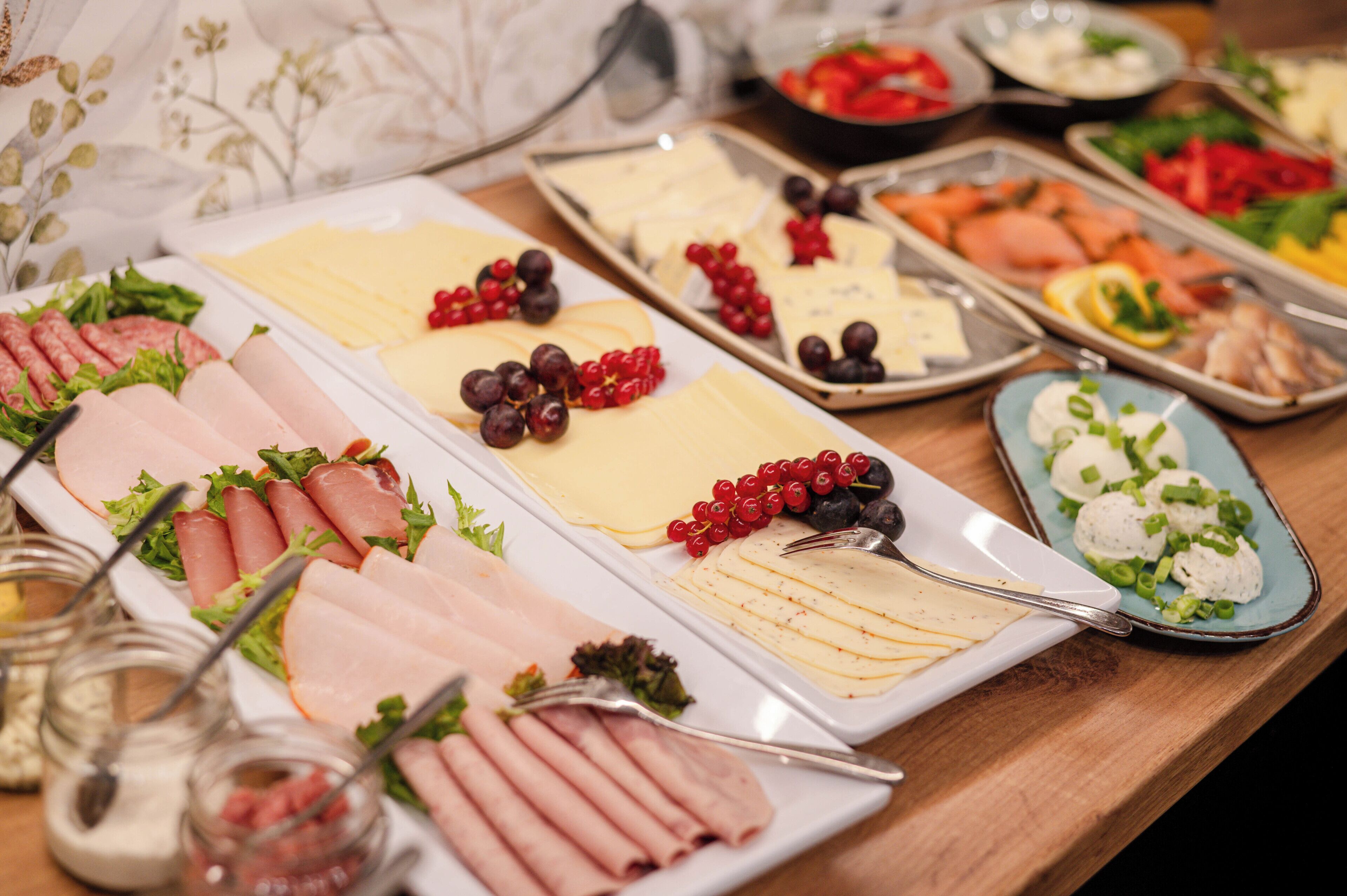 Un bufé con diversas opciones de comida, incluyendo carnes, quesos y frutas.