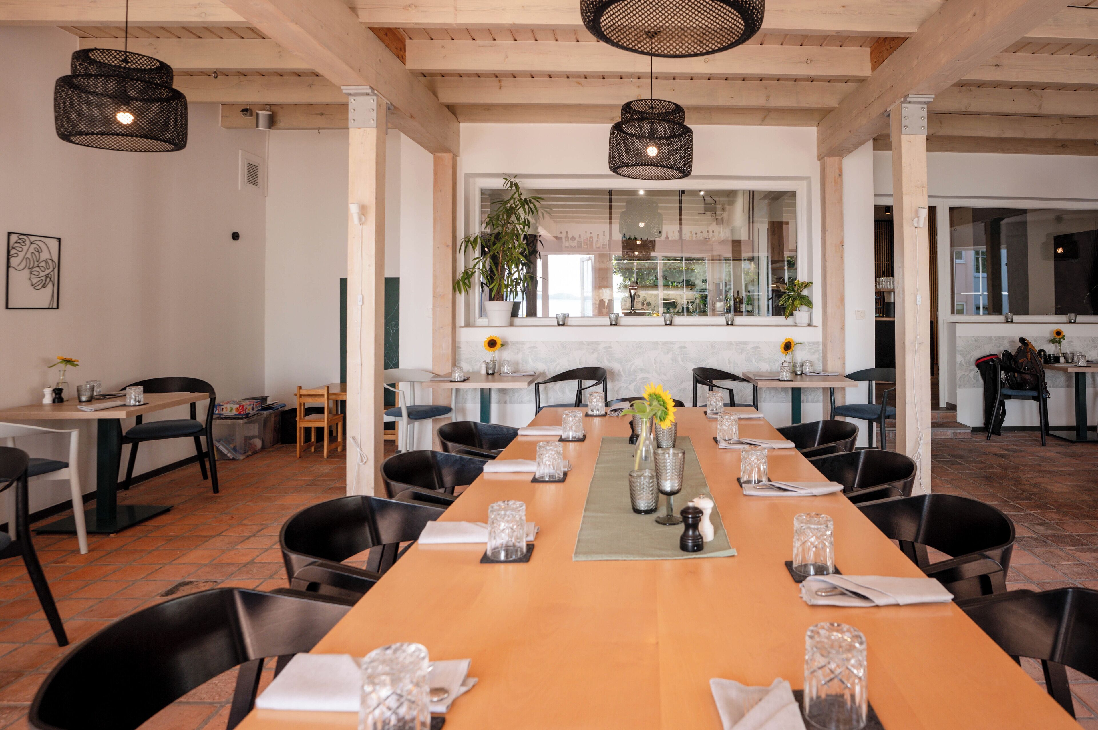 A spacious dining area with a long wooden table set for a meal, surrounded by black chairs.