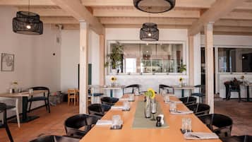 A spacious dining area with a long wooden table set for a meal, surrounded by black chairs.