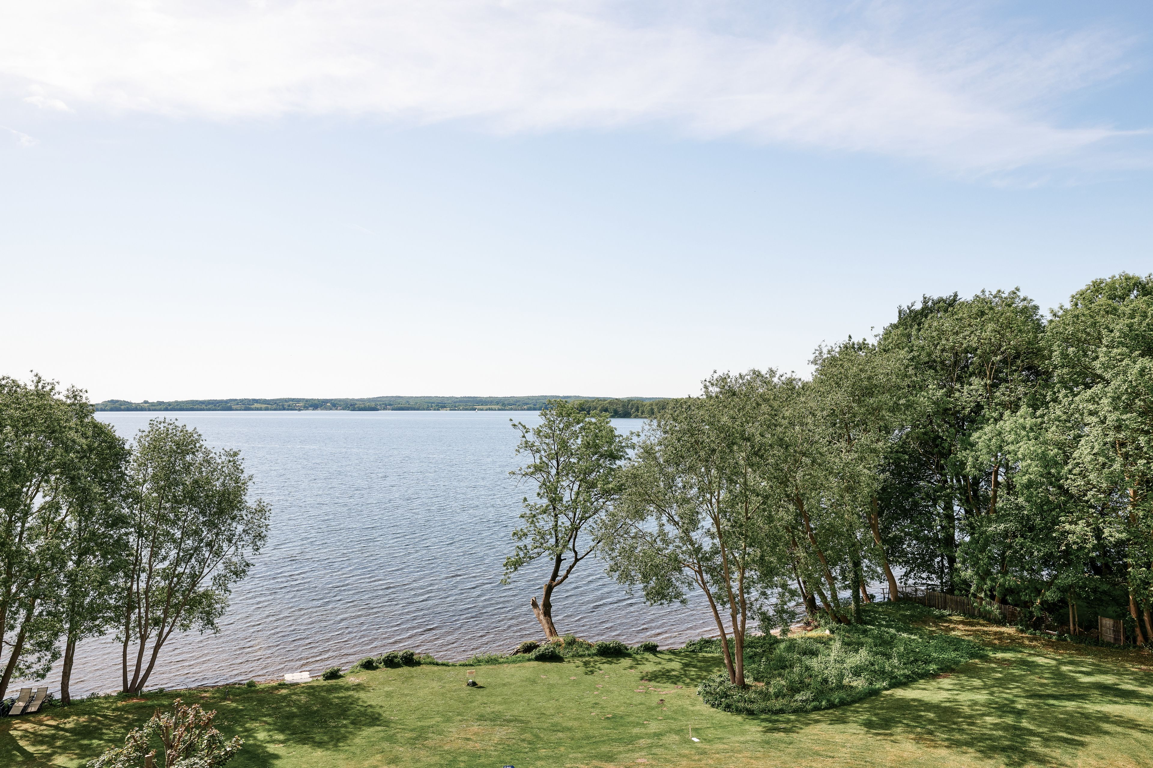 A lakeside view with a grassy area and trees.