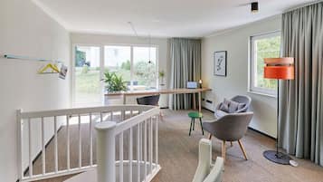 Step up to a spacious room with a desk for work, a cozy seating area, and large windows offering a view of the outdoors.