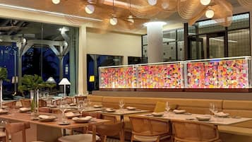 Interior de restaurante con mobiliario de madera, piso estampado y decoración de pared colorida.