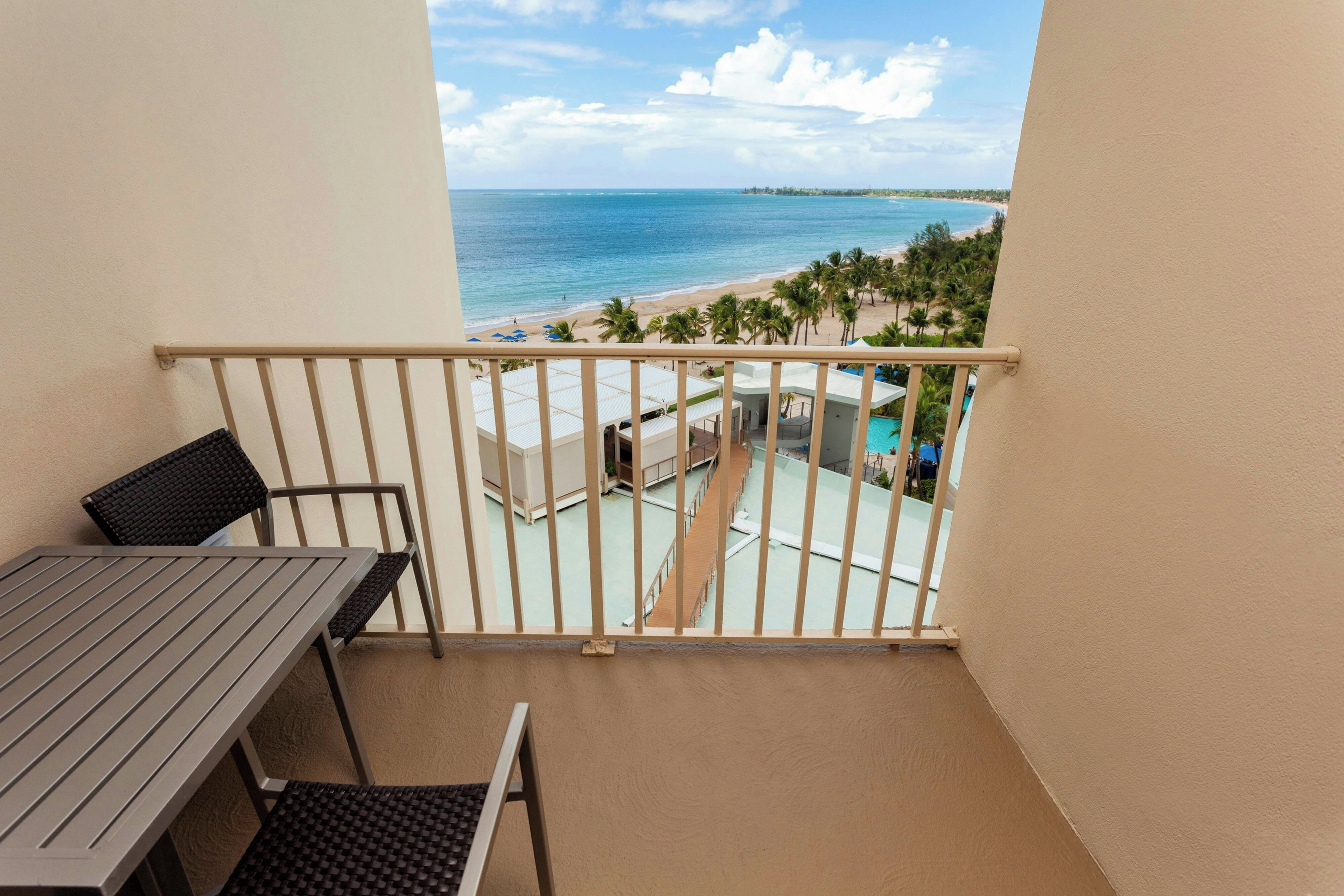 A balcony with a view of a beach and a pool.