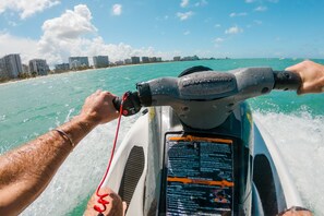 A jet ski with a warning label and a city skyline in the background.