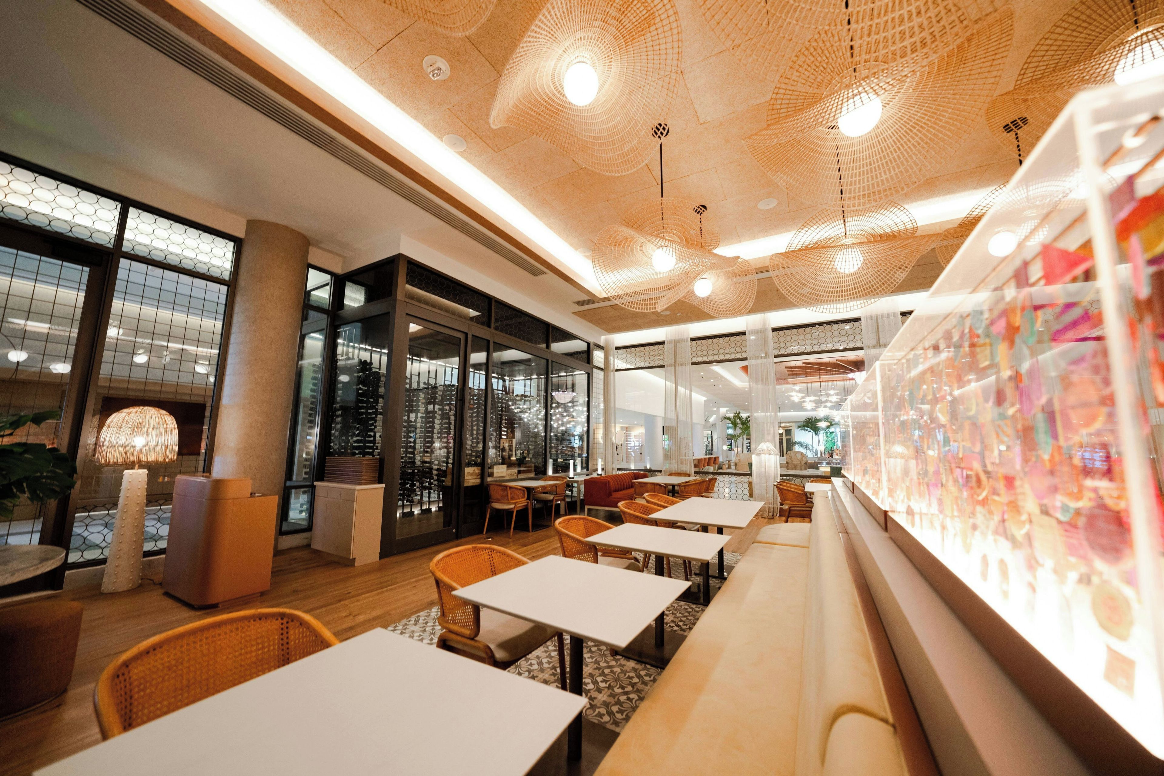 A modern interior with a long counter, seating area, and large windows.