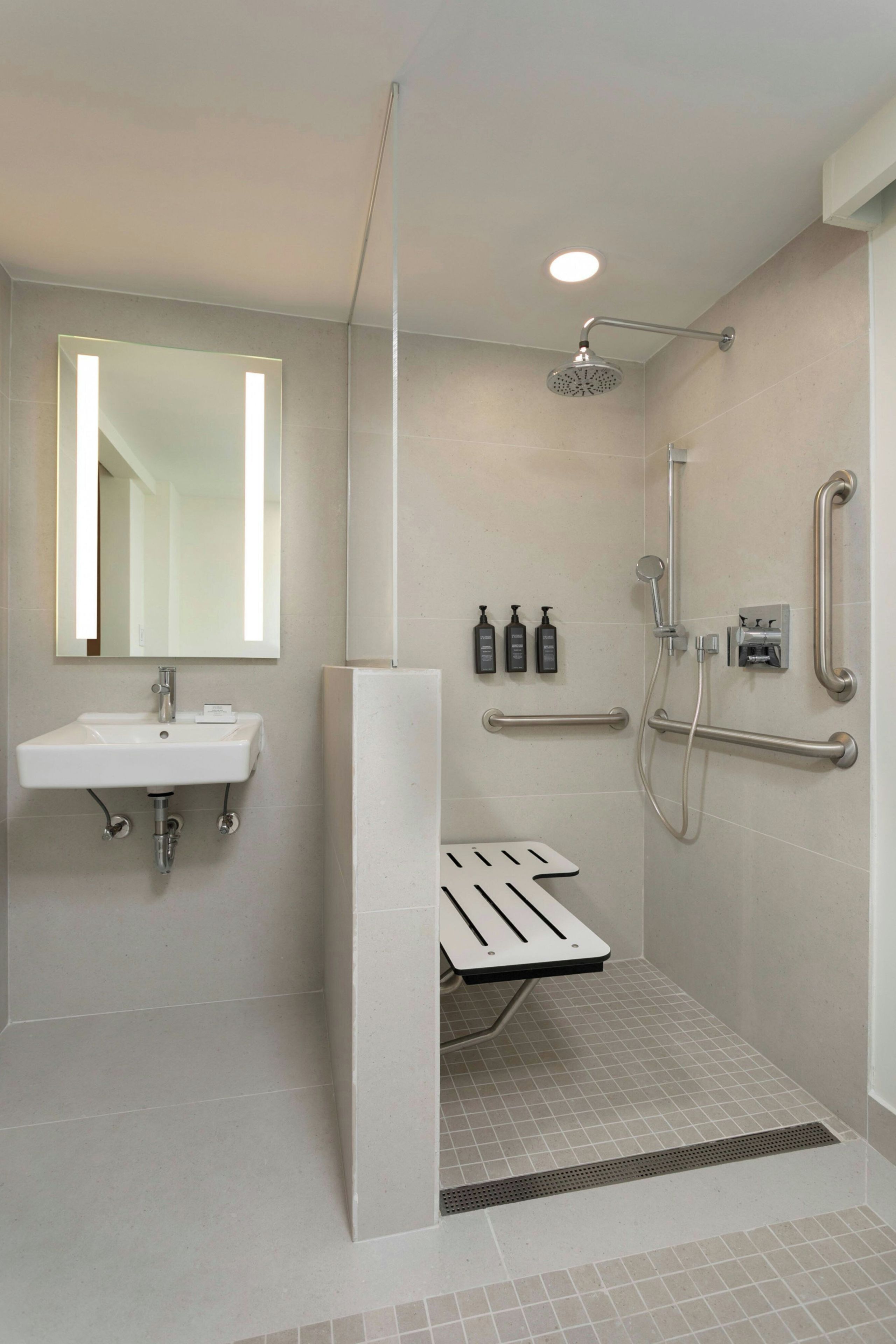 A modern bathroom with a shower, a sink, and a mirror.