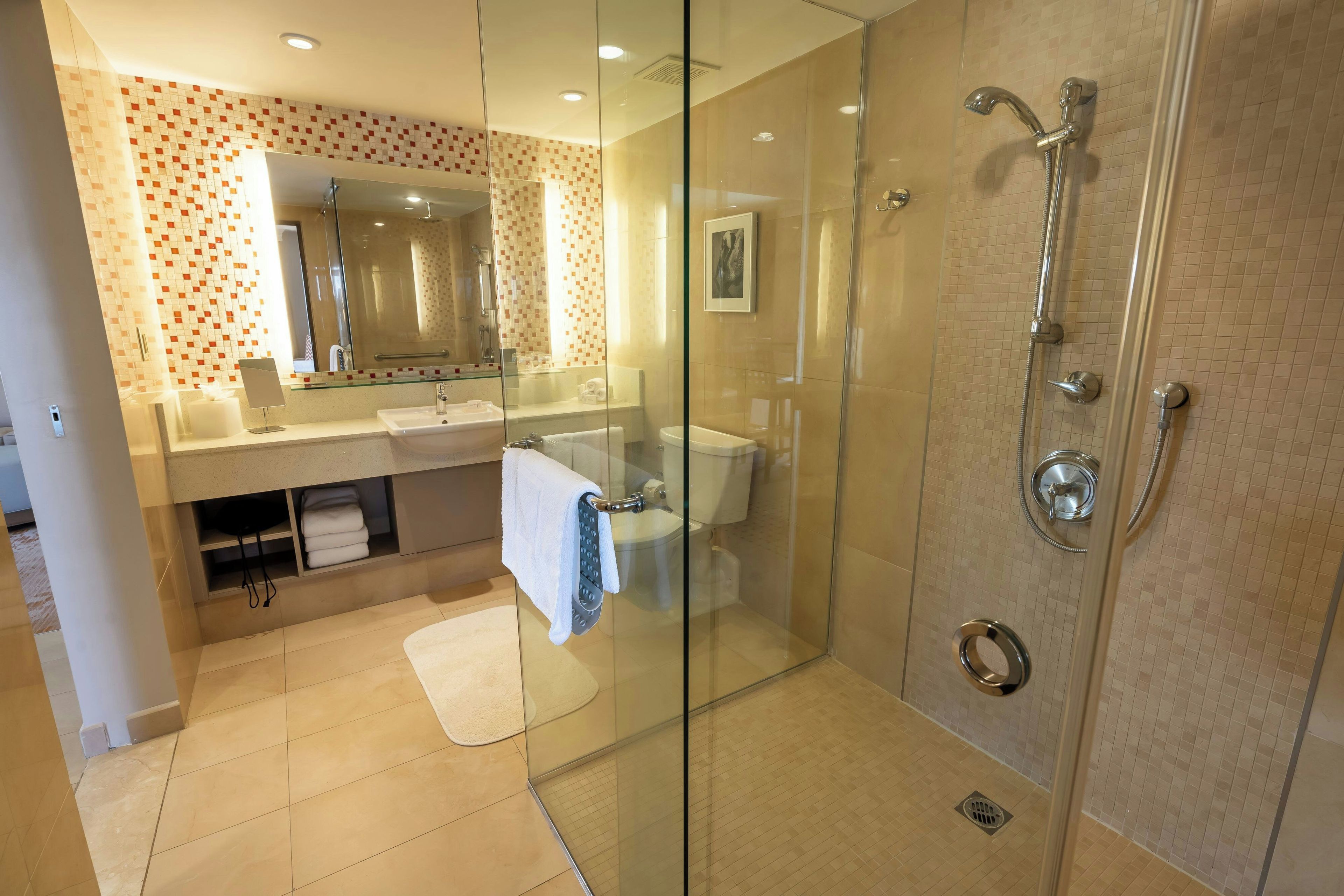 Ein modernes Badezimmer mit einer gläsernen Duschkabine, einem Waschtisch mit Spiegel und einer Toilette.
