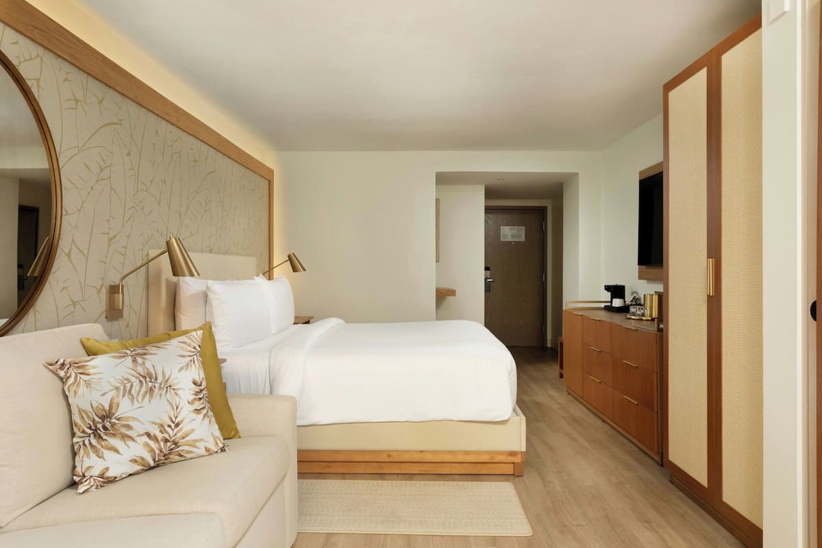 Een slaapkamer met een bed, een slaapbank, een kledingkast en een spiegel.