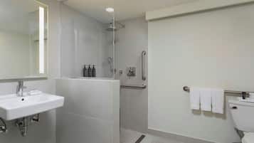 Un baño moderno con lavamanos, espejo, ducha e inodoro.