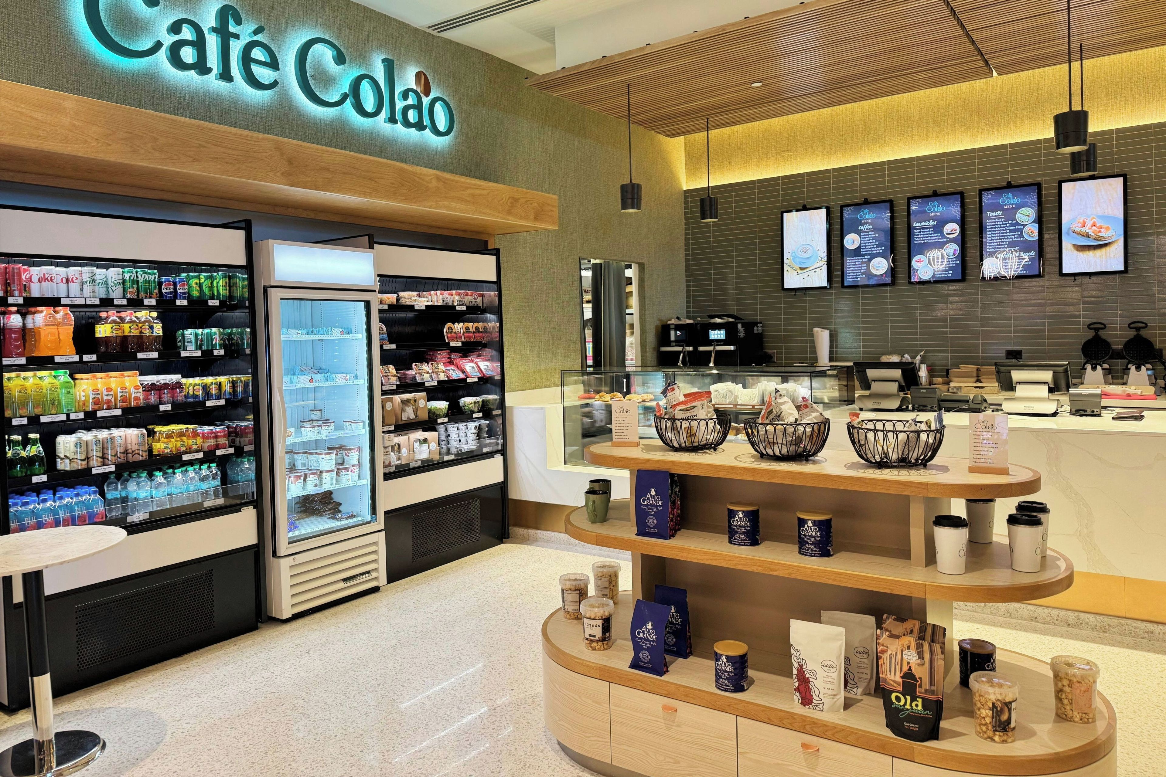 Una cafetería con una vitrina refrigerada de bebidas, una barra de café y un panel de menú.