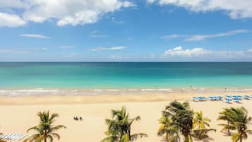 A beach with clear turquoise waters, a sandy shore, and palm trees.
