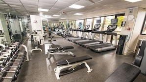 A gym with treadmills, dumbbells, and weight machines.