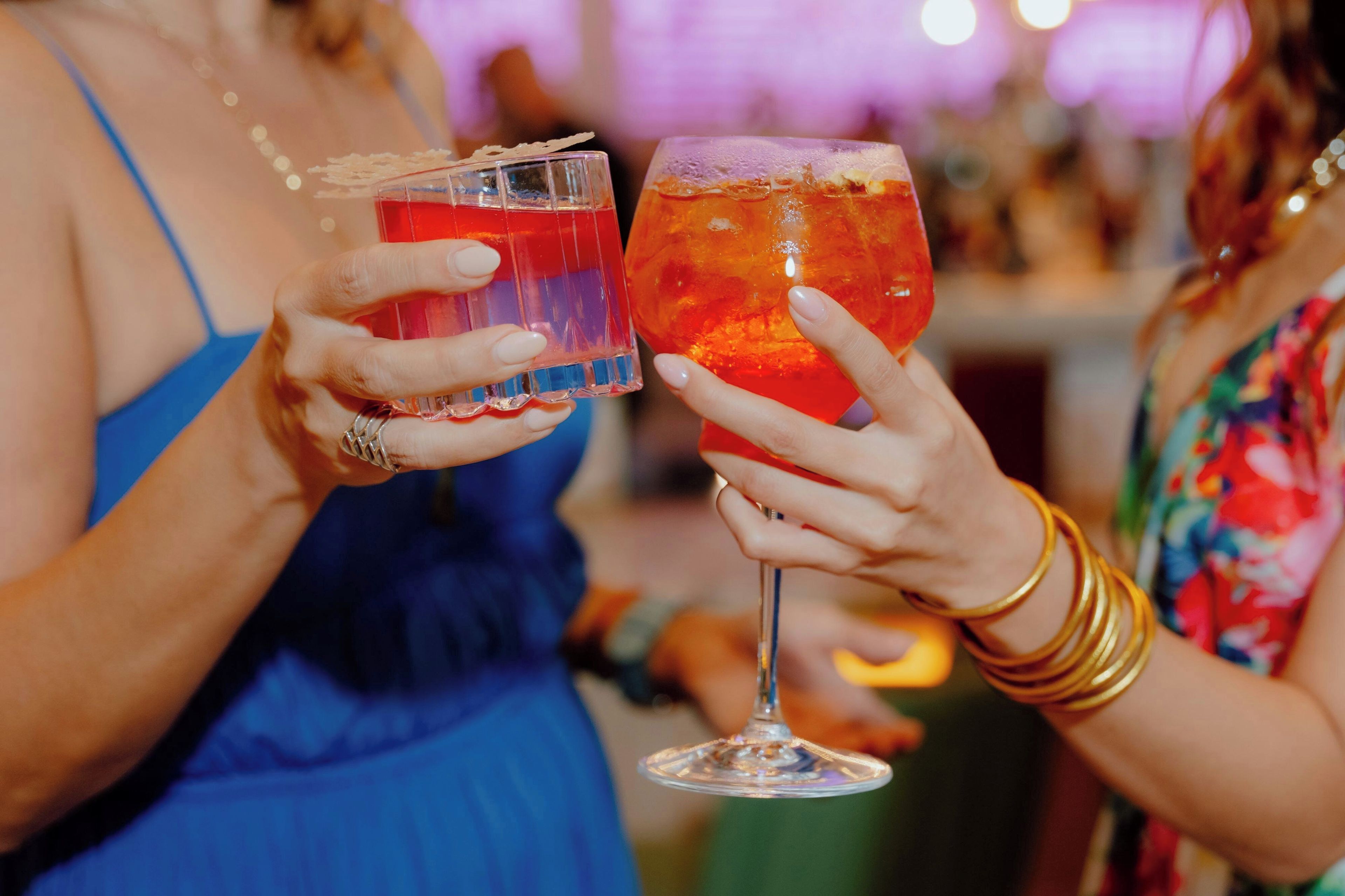 Two people holding glasses of red beverages, likely cocktails, at a social event.