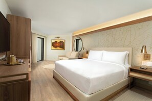 Una habitación de hotel moderna con una cama grande, un escritorio, una silla y un televisor.
