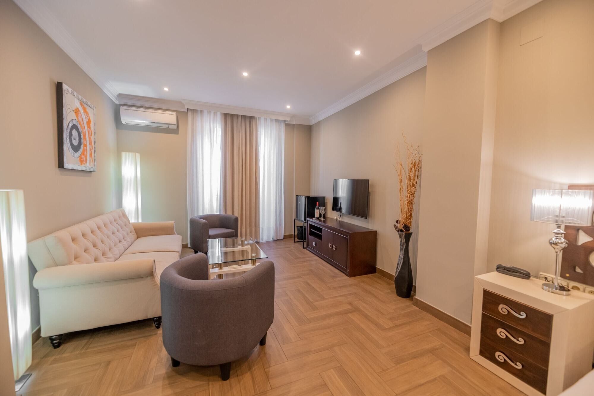 A modern living room with a sofa, armchair, TV, and entertainment unit.