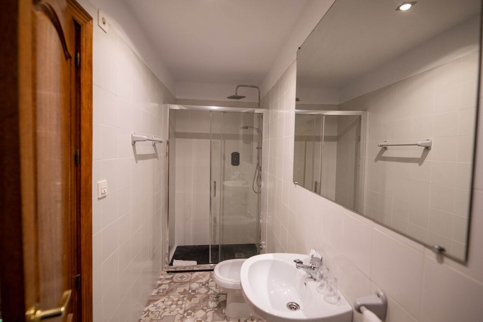 Un baño con ducha, lavamanos y espejo.
