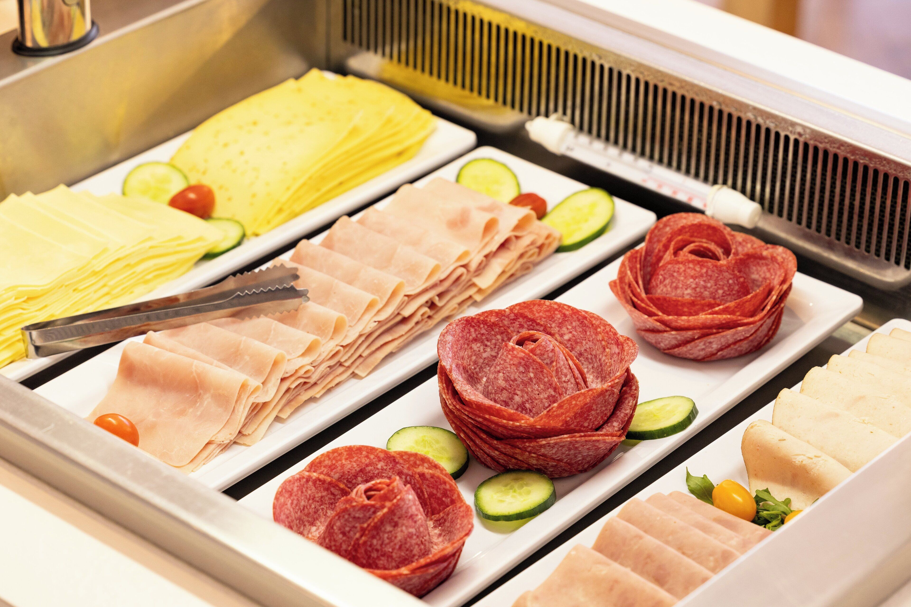 Ein Buffet mit verschiedenen Speisen, darunter Aufschnitt, Käse und Gemüse.