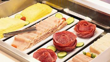 Ein Buffet mit verschiedenen Speisen, darunter Aufschnitt, Käse und Gemüse.