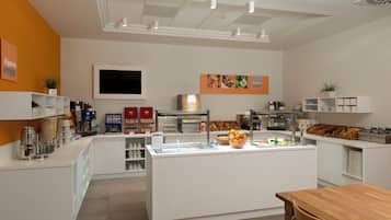 A modern cafe with a central counter, coffee machines, and a variety of food items.