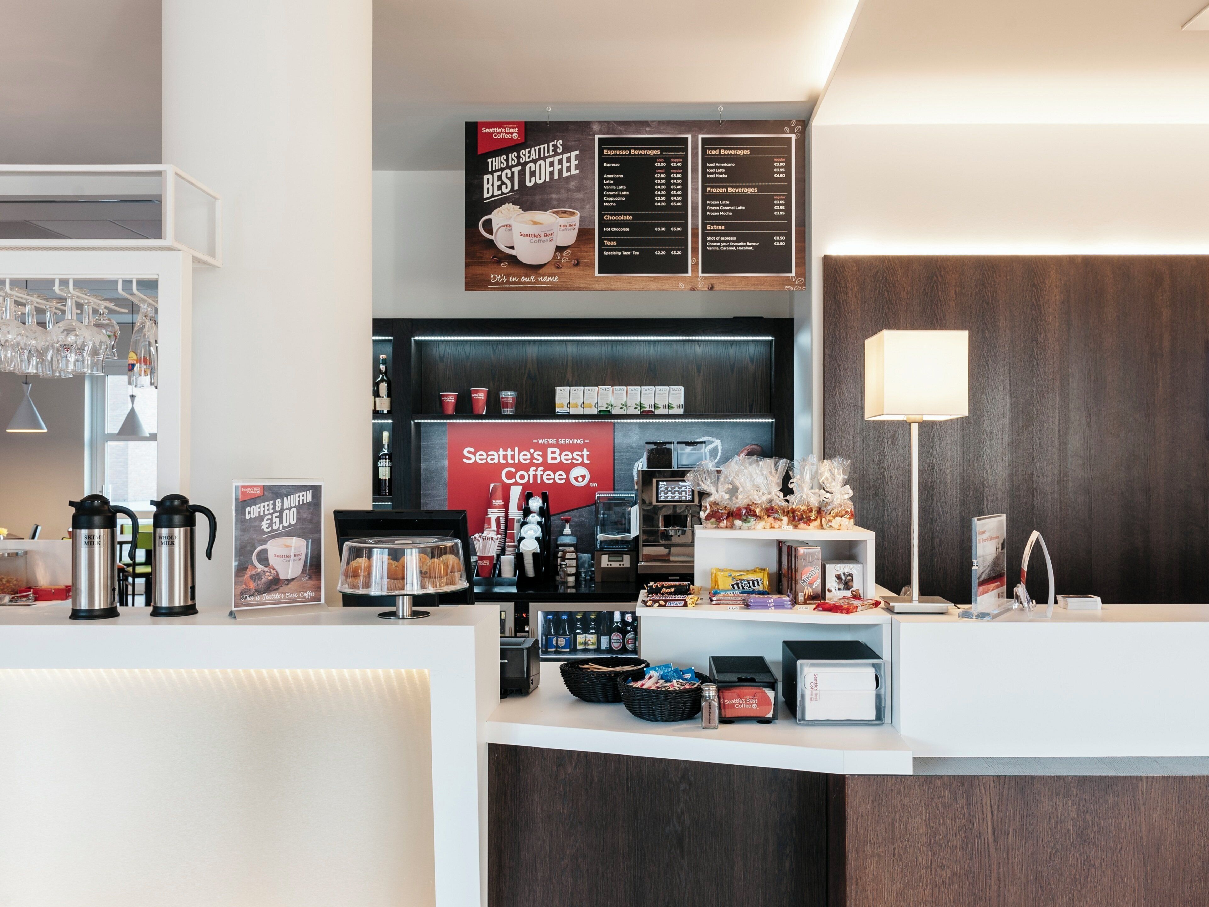 A coffee shop interior with a menu board, espresso and iced beverage options, and a counter with coffee-making equipment.