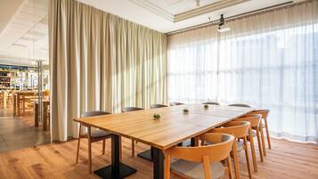Una sala de conferencias con una mesa de madera, sillas y un amplio ventanal con cortinas.
