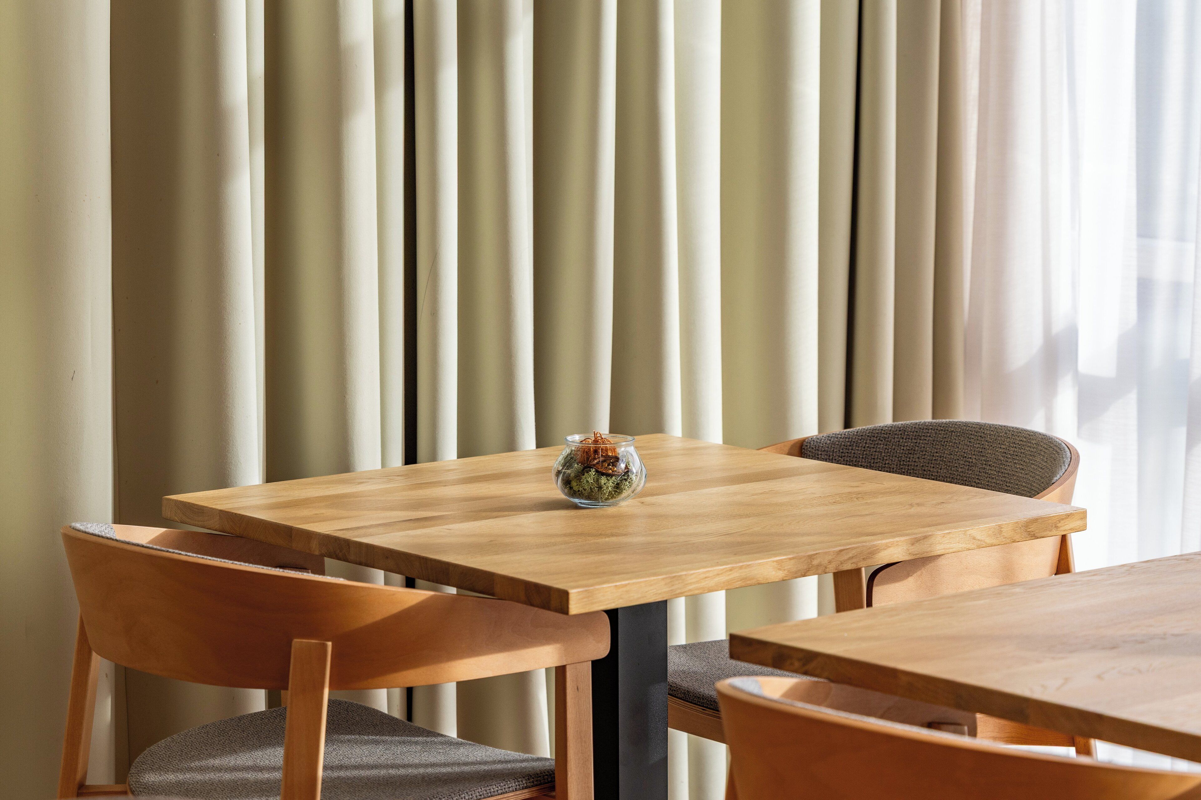 A wooden table with a glass vase and a chair in front of it.