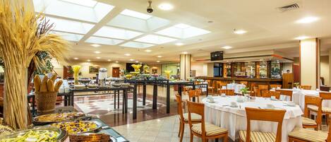 Zona de bufé con diversas opciones de comida y un bar al fondo.