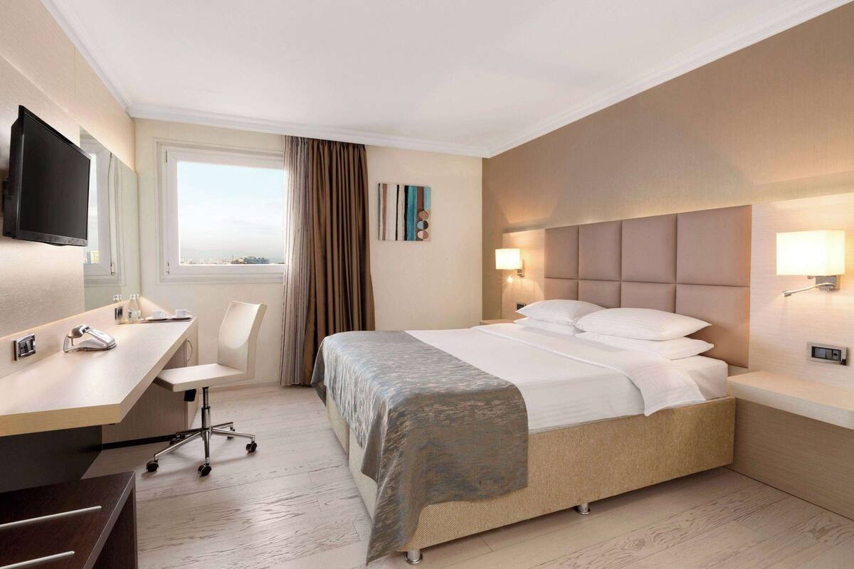 Une chambre d’hôtel équipée d’un lit, d’un bureau, d’une chaise et d’un téléviseur.