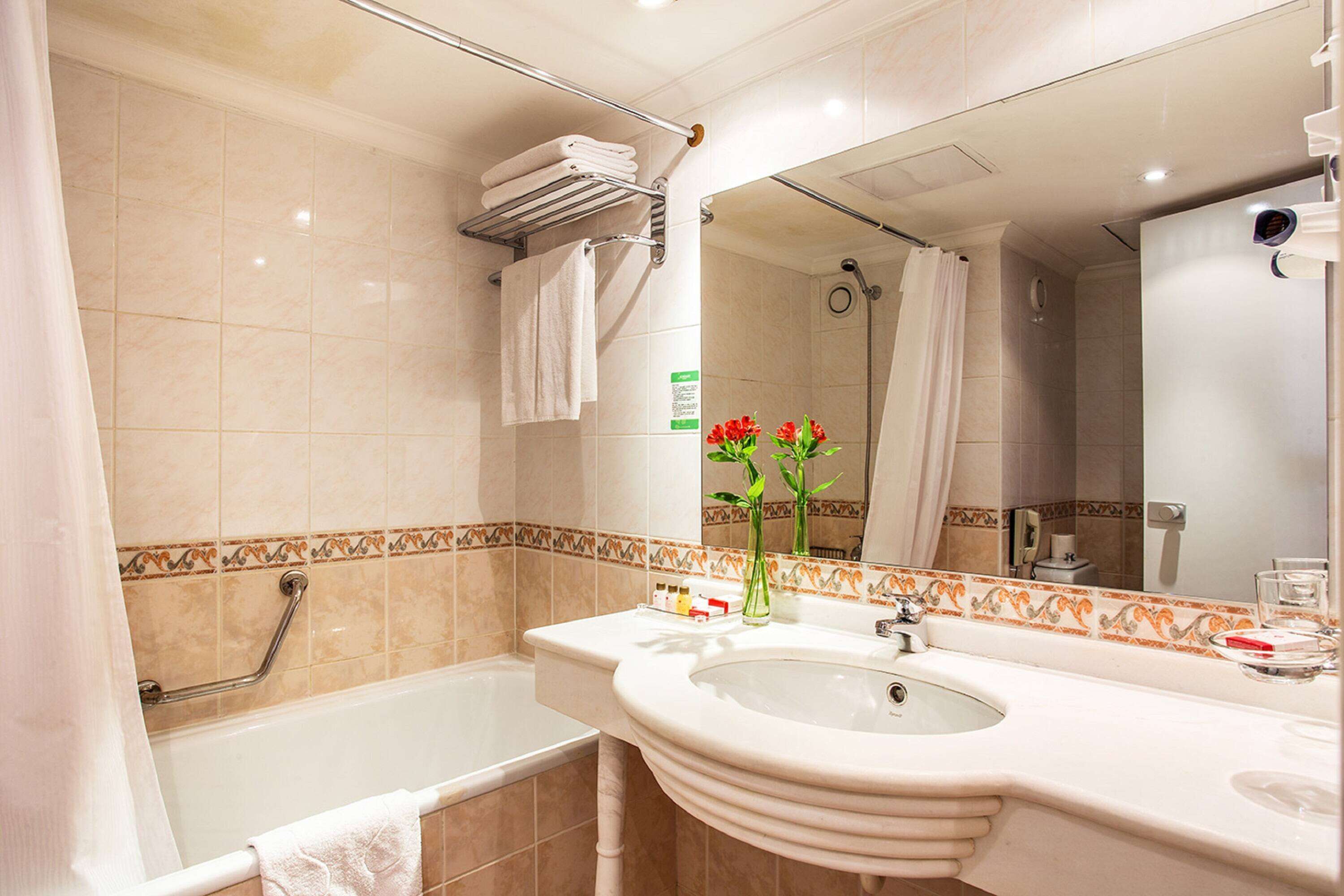 Une salle de bain avec une baignoire, un lavabo, un miroir et un espace douche.