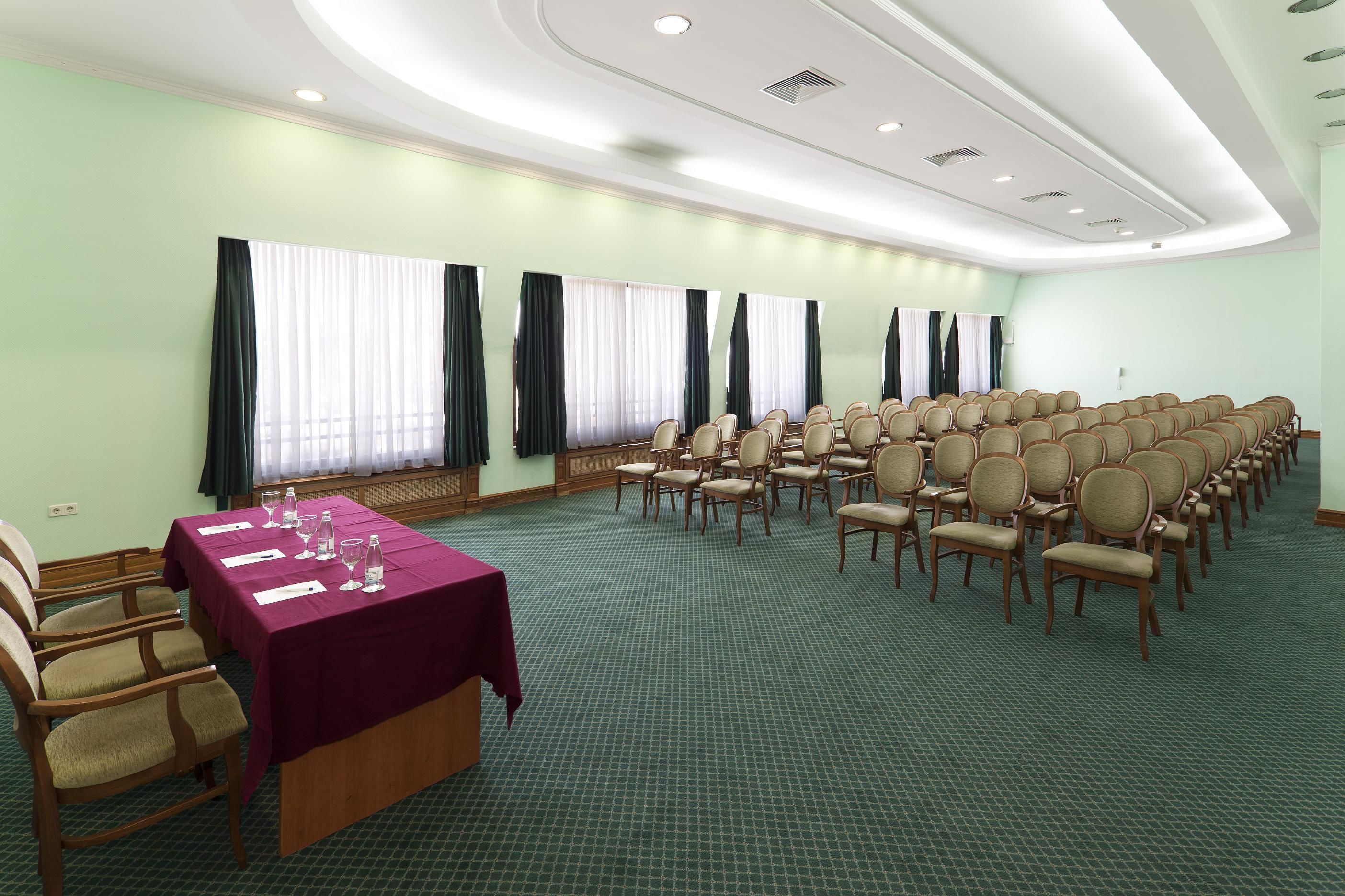 Un salón de conferencias con una larga mesa, varias sillas y piso alfombrado.