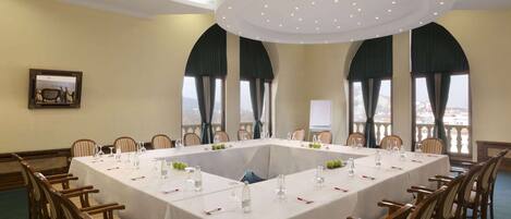 A conference room with a large table, chairs, and a view through the windows.