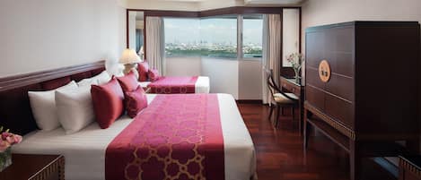 A hotel room with a large bed, a desk, and a view of a cityscape.