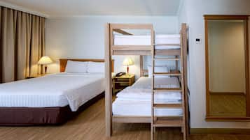 Una habitación de hotel con una cama litera, una mesita de noche con lámpara, un armario y un atril.