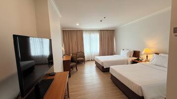 A hotel room with two beds, a TV, a desk, and a chair.