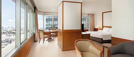 Una habitación de hotel con un ventanal grande, una cama, un escritorio, una silla y un sofá.