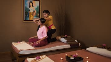 Une salle de massage équipée de deux tables de massage, d’un tableau au mur et de bougies posées sur les tables.