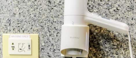 Un secador de pelo conectado a un enchufe de pared con un interruptor que indica 'SOLO AFEITAR'.