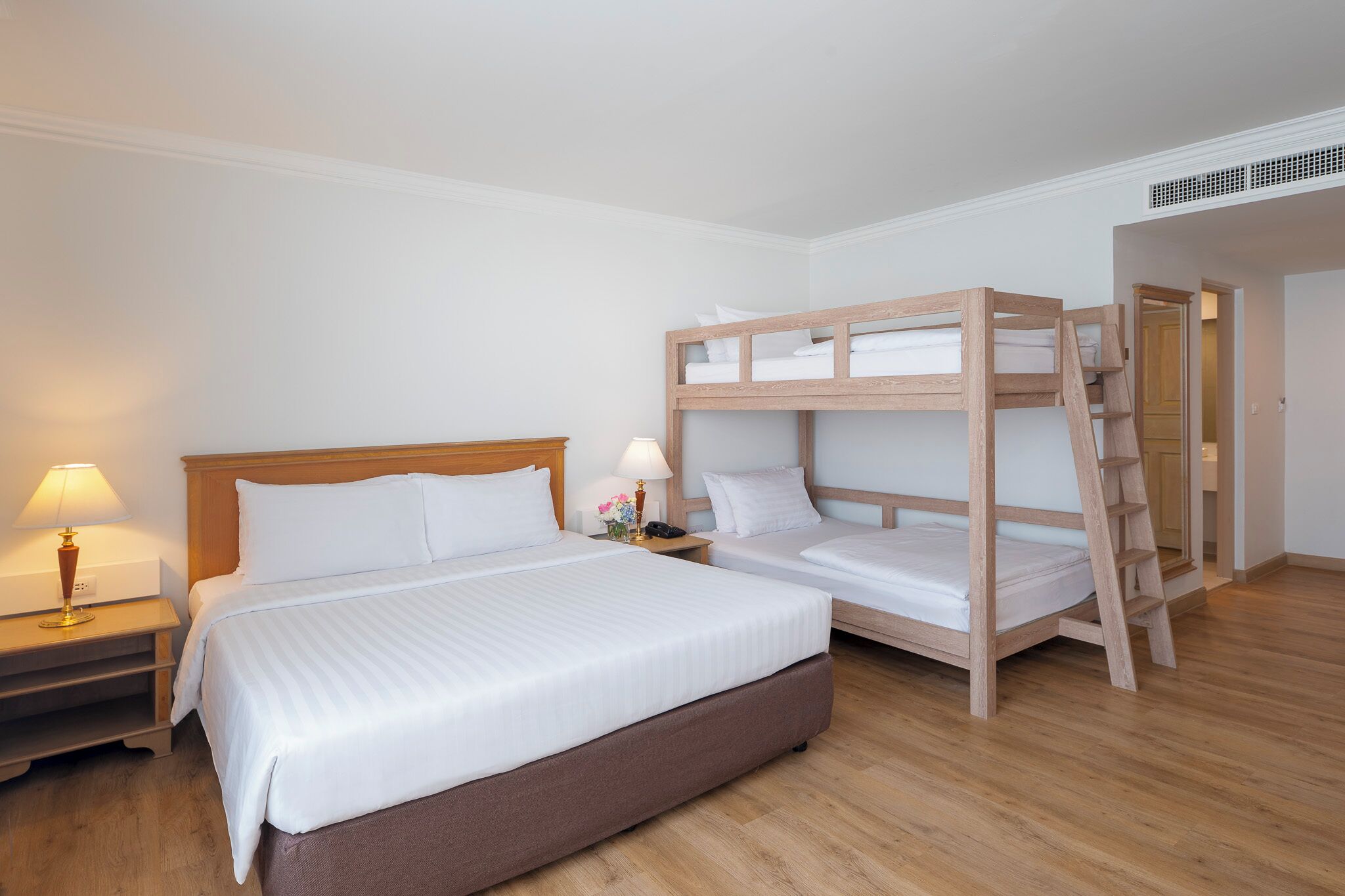 Ein Zimmer mit einem großen Bett, einem kleineren Bett, einem Nachttisch mit einer Lampe und einer Holzleiter.