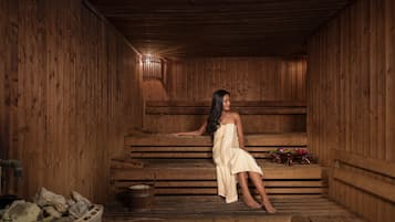 A wooden sauna with benches and a bucket of rocks.