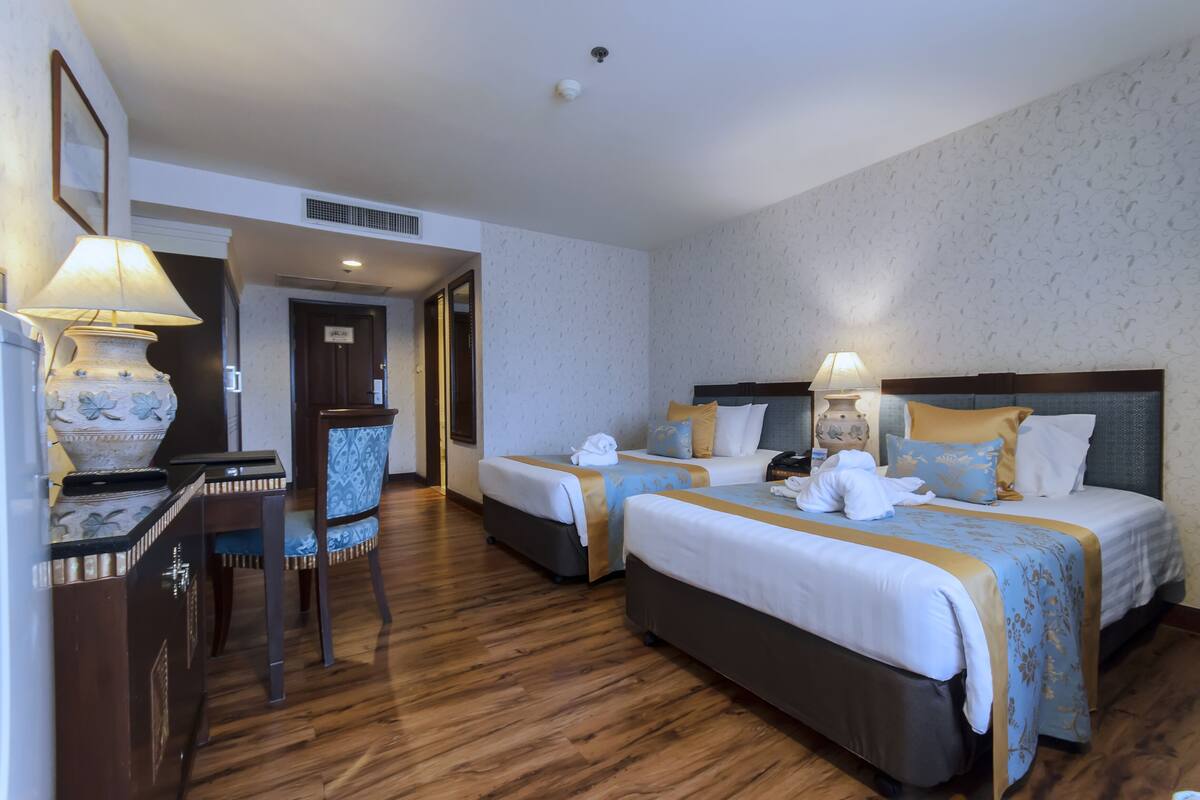 Ein Hotelzimmer mit zwei Betten, einem Schreibtisch und einem Stuhl.