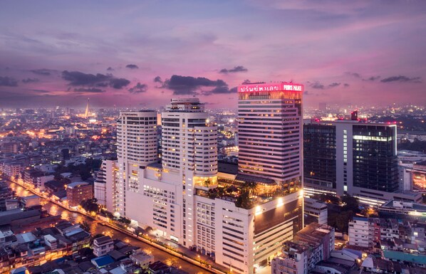A cityscape with modern high-rise buildings, a river, and a sunset sky.