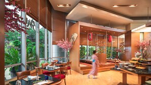 A modern restaurant with large windows, wooden furniture, and a variety of dishes displayed on tables. - Prince Palace Hotel Bangkok (Bangkok)