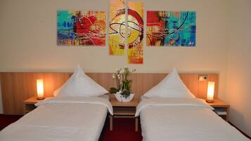 A hotel room with two beds, a wooden headboard, bedside lamps, and a wall with abstract art.